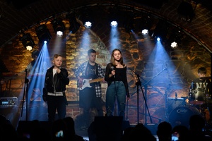 Koncert S.M.ROCK: na scenie uczennice i uczniowie  wykonujący piosenkę przed publicznością