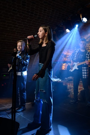 Koncert S.M.ROCK: na scenie uczennice i uczniowie  wykonujący piosenkę przed publicznością