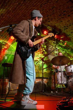 Koncert: The Flash! - Kuba Dworak grający na gitarze basowej, w tle Max Olszewski grający na perkusji.
