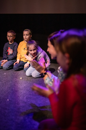Filmowe ferie w kinie Marzenie - Na fotografii widzimy grupę dzieci siedzących w półkolu na scenie przed ekranem, podczas animacji poprzedzających projekcje filmowe w ramach cyklu "Filmowe ferie".