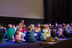 Filmowe ferie w kinie Marzenie - Na fotografii widzimy grupę dzieci na scenie przed ekranem, podczas animacji poprzedzających projekcje filmowe w ramach cyklu "Filmowe ferie".