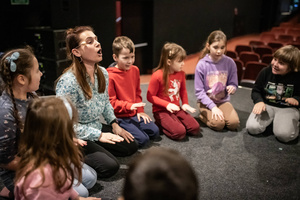 Filmowe ferie w kinie Marzenie - Na fotografii widzimy grupę dzieci siedzących w półkolu na scenie przed ekranem, podczas animacji poprzedzających projekcje filmowe w ramach cyklu "Filmowe ferie".