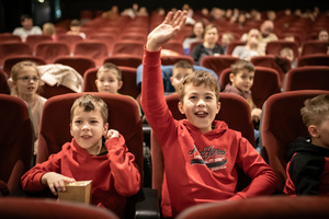 Filmowe ferie w kinie Marzenie - Na fotografii widzimy grupę dzieci na scenie przed ekranem, podczas animacji poprzedzających projekcje filmowe w ramach cyklu "Filmowe ferie".