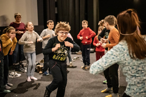 Filmowe ferie w kinie Marzenie - Na fotografii widzimy grupę dzieci siedzących w półkolu na scenie przed ekranem, podczas animacji poprzedzających projekcje filmowe w ramach cyklu "Filmowe ferie".