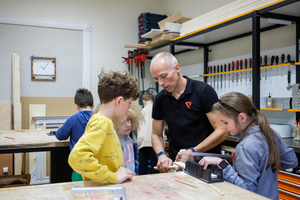 Naukowe Ferie w Pasażu Odkryć - Na zdjęciu przedstawieni są uczestnicy – dzieci i młodzież – zaangażowani w aktywności edukacyjne w różnych pracowniach naukowych, takich jak chemiczna, stolarska, planetarium oraz informatyczna. Widoczne są sceny, gdzie uczą się i przeprowadzają eksperymenty pod nadzorem instruktorów.