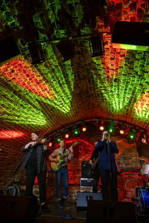 Koncert jazzowy: Tomasz Chyła Quintet - Zdjęcie sceny z koncertu Tomasz Chyła Quintet, pokazujące zaangażowanych muzyków. Tomasz Chyła gra na skrzypcach, w tle pozostali muzycy na różnych instrumentach. Scena jest dynamicznie oświetlona, co dodaje energii występowi.