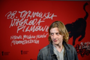 38. TNF - Dzień 3 (2.06.2024) - Odtwórca jednej z głównych ról w filmie "Kobieta z..." Mateusz Więcławek na tle ścianki festiwalowej w holu Marzenia