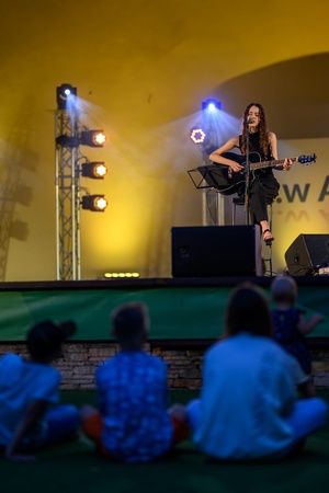 Koncert: "Ballady na głos i gitarę" - Łucja Kania - Na scenie śpiewająca i grająca na gitarze Łucja Kania