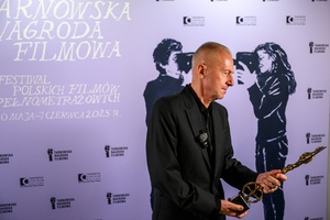 39. TNF: Gala Wręczenia Nagród (7.06.2025) - W hallu kina na tle ścianki 39. TNF aktor Bogusław Linda ze statuetką Włóczykija za całokształt