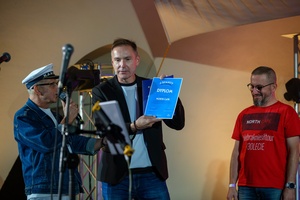 Szanty na Starówce: Kliper Marzenie, North Cape - Na scenie dyrektor TCK Tomasz Kapturkiewicz prezentujący publiczności dyplom dla North Cape