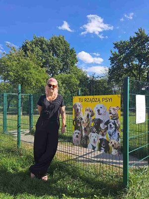 Tu rządzą psy - akcja społeczna - Pomysłodawczyni akcji - Dorota Omylska - stoi obok tablicy z psami