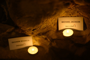 Koncert: Zaduszki - Damian Ukeje - Element scenografii - etykiety z nazwiskami nieżyjących artystów oświetlone świeczkami.