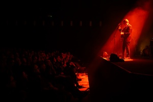 Koncert: John Porter - Helicopters'45 - Na scenie John Porter z gitarą przemawiający do publiczności