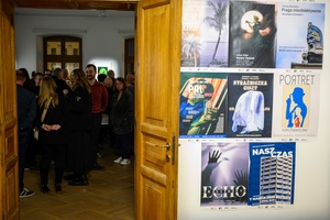 Wystawa: w cyklu Wernisaże Dzień po Dniu - Plakaty wystaw w cyklu wernisaże Dzień po Dniu a w głębi sali publiczność oglądająca wystawę.