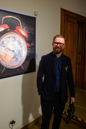 Wystawa: Rozważania nad istotą czasu - Marcin Dąbek z aparatem autora wystawy, przy jednej z jego fotografii.
